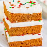 Three gingerbread bars stacked tall showing the soft spiced crumb and thick cream cheese frosting.