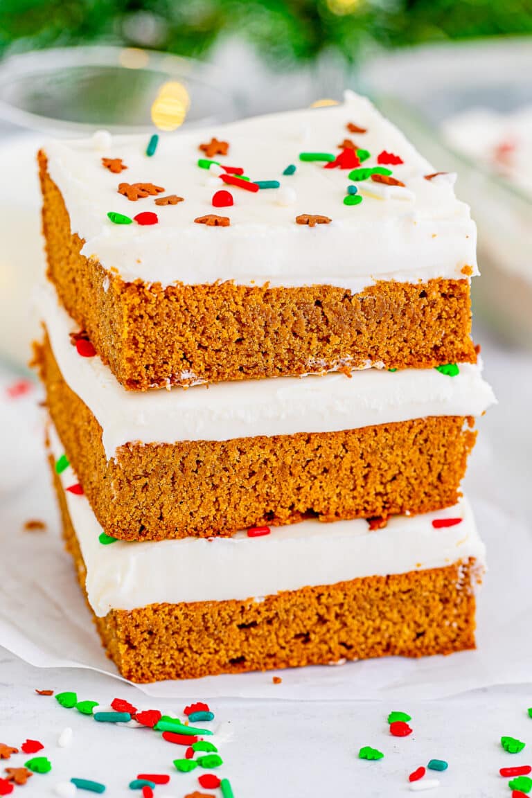 Three gingerbread bars stacked tall showing the soft spiced crumb and thick cream cheese frosting.