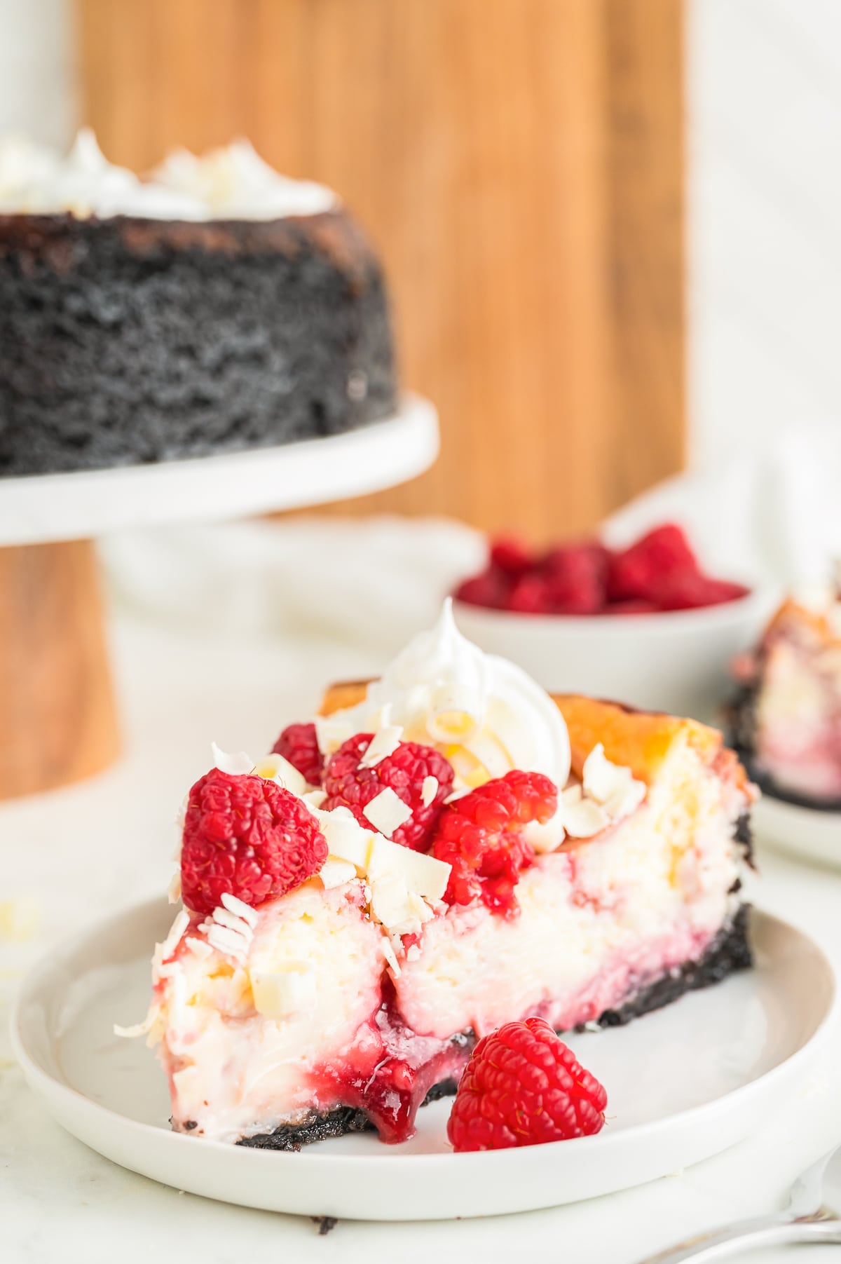 a slice of White Chocolate and Raspberry Cheesecake on a white plate