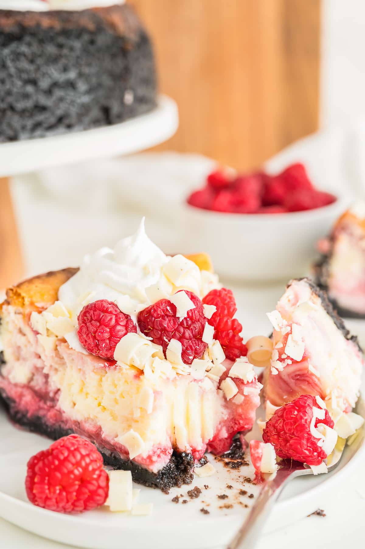 a slice of White Chocolate and Raspberry Cheesecake on a white plate with a bite taken out