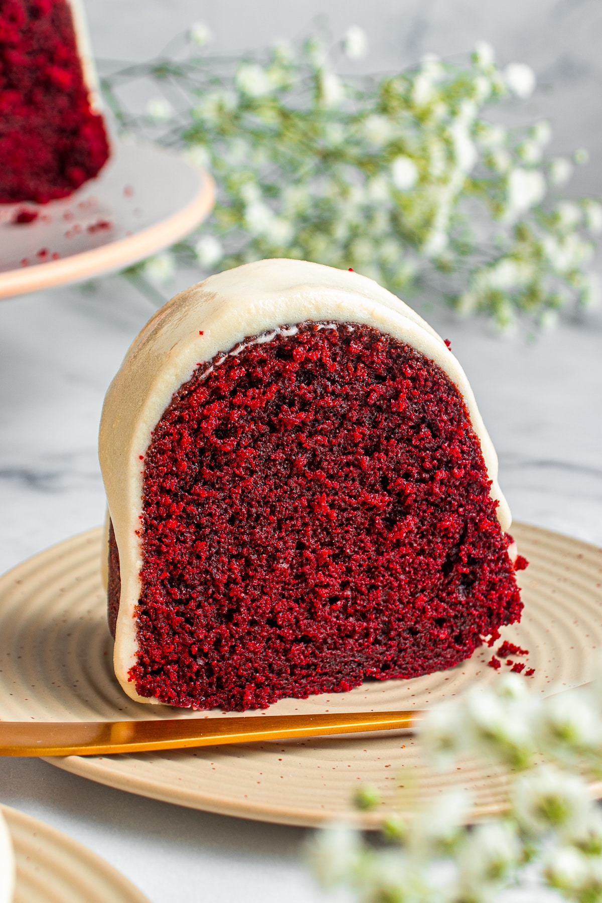 a slice of Red Velvet Bundt Cake on a tan plate