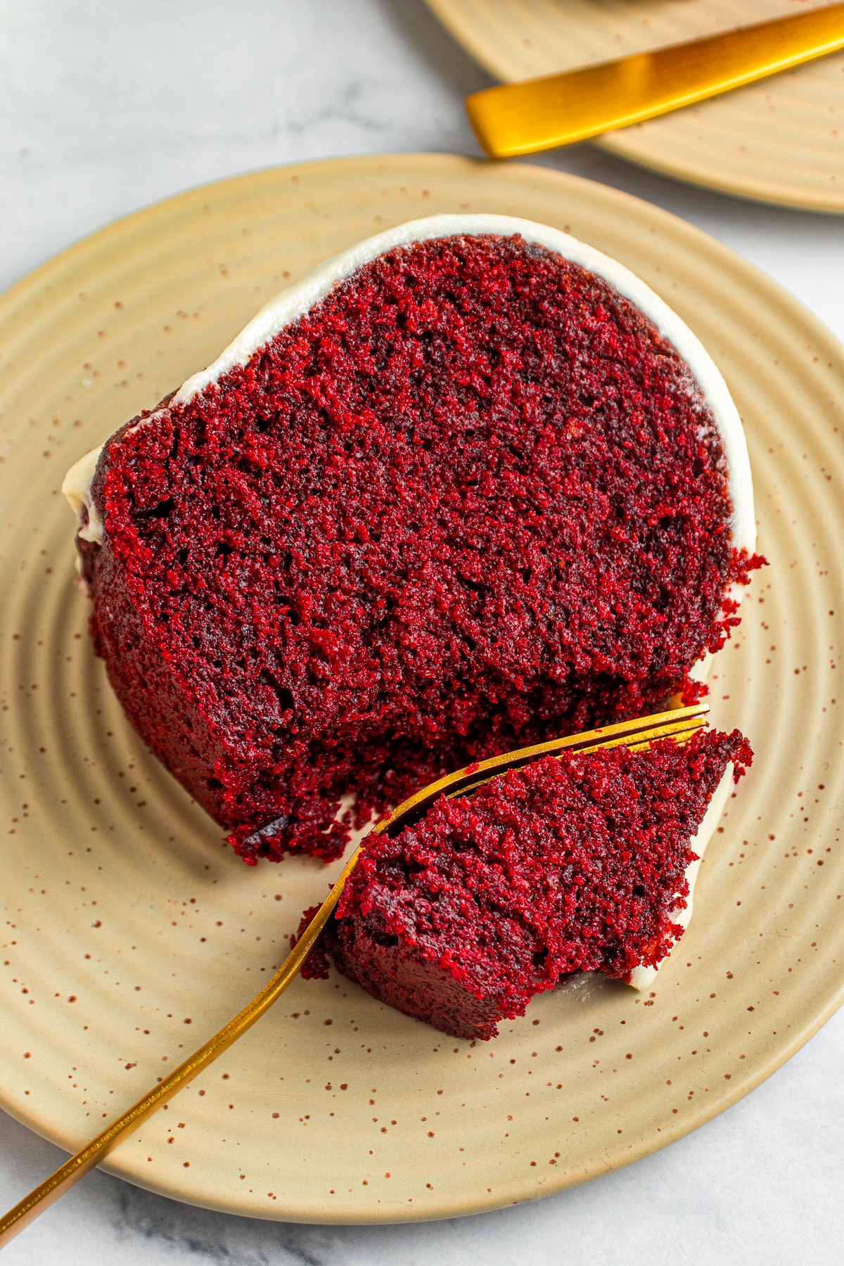 a fork grabbing a bite of Red Velvet Bundt Cake on a tan plate