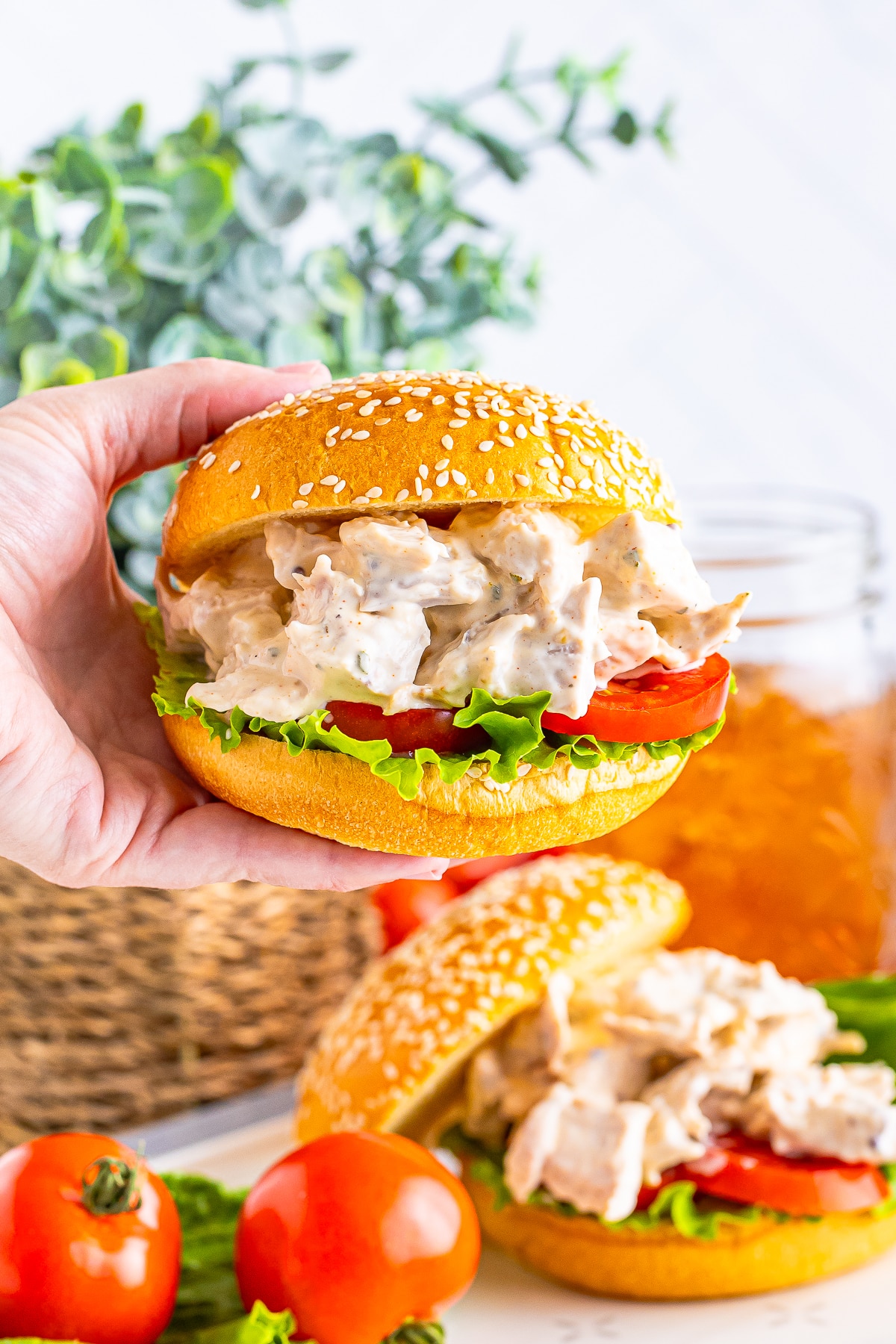 a hand holding up Rotisserie Chicken Salad in a sandwich in air