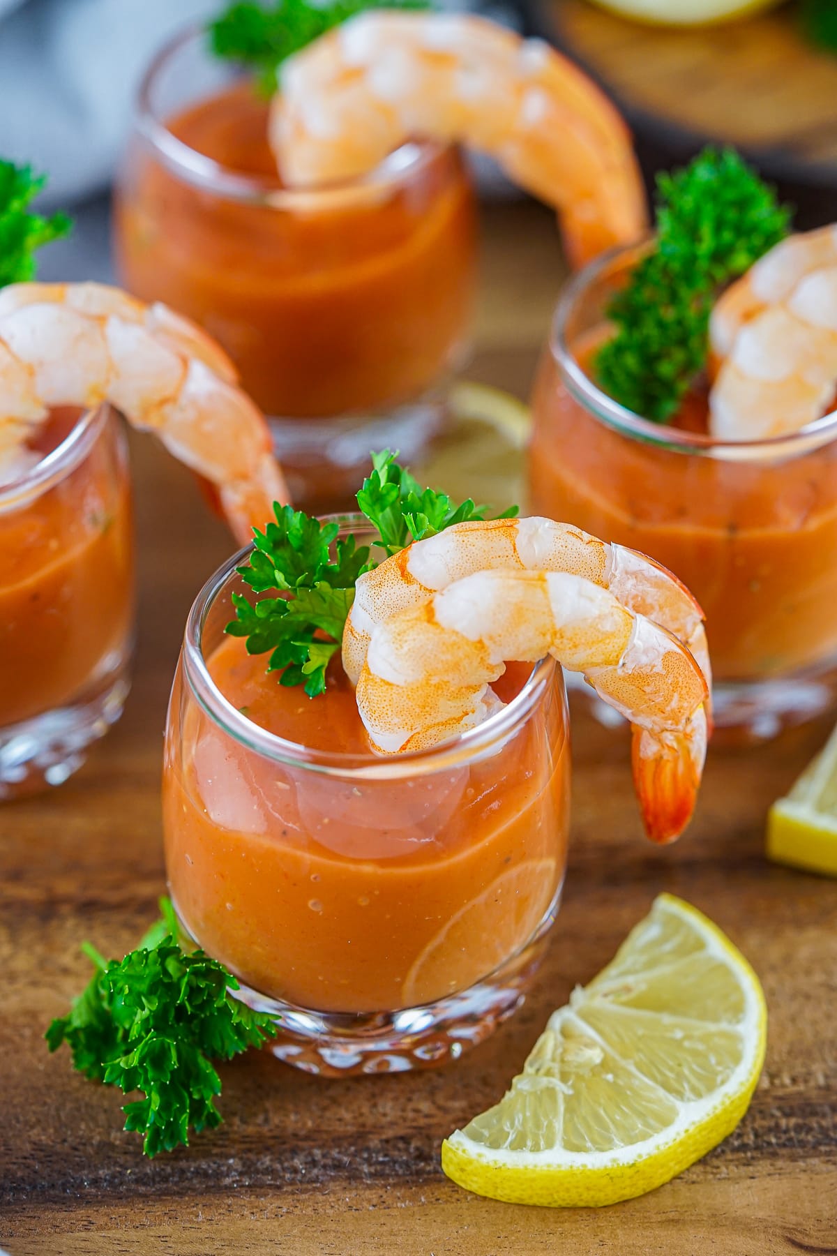 Cocktail Shrimp lined up in glass on a wooden platter