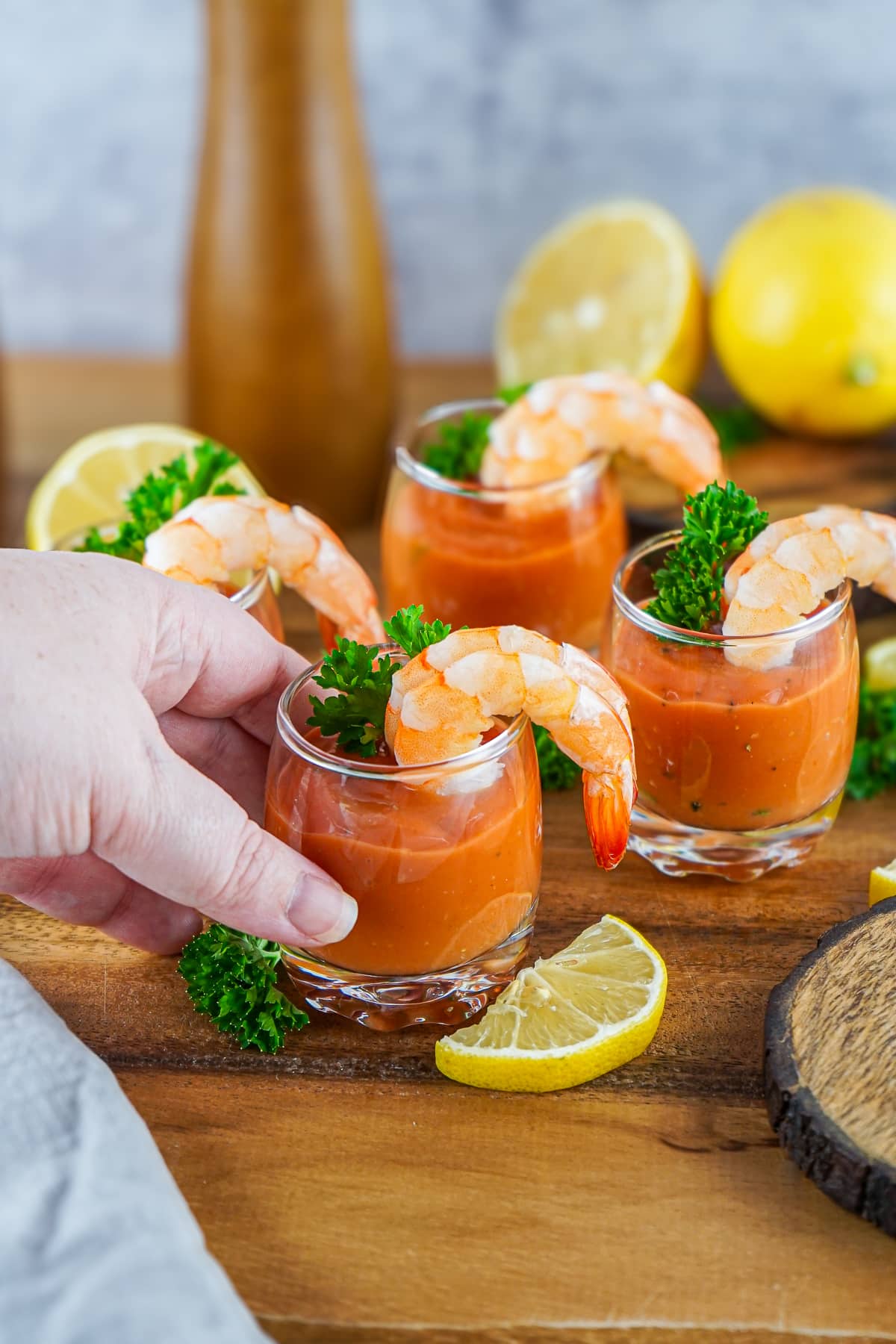a hand grabbing one of the glasses of Cocktail Shrimp