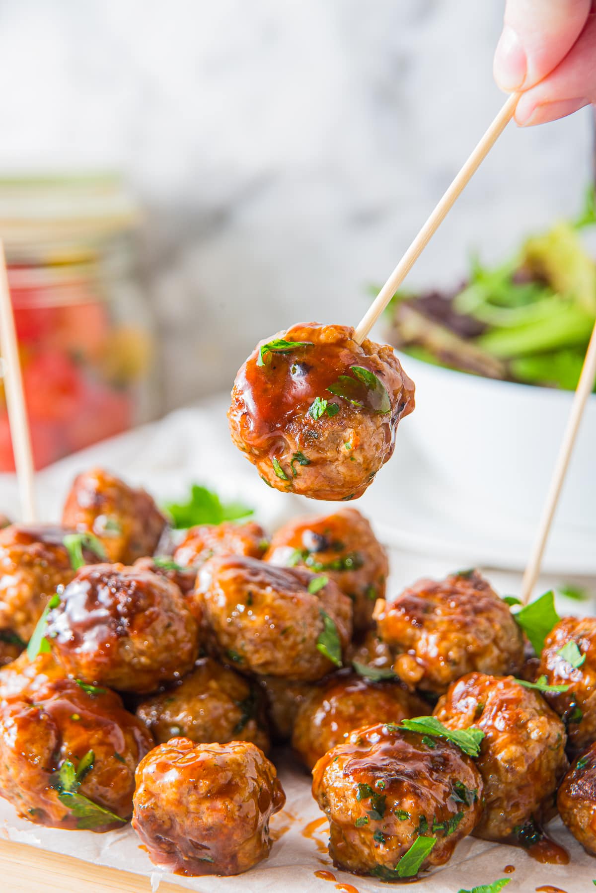 a toothpick holding up BBQ meatballs in air