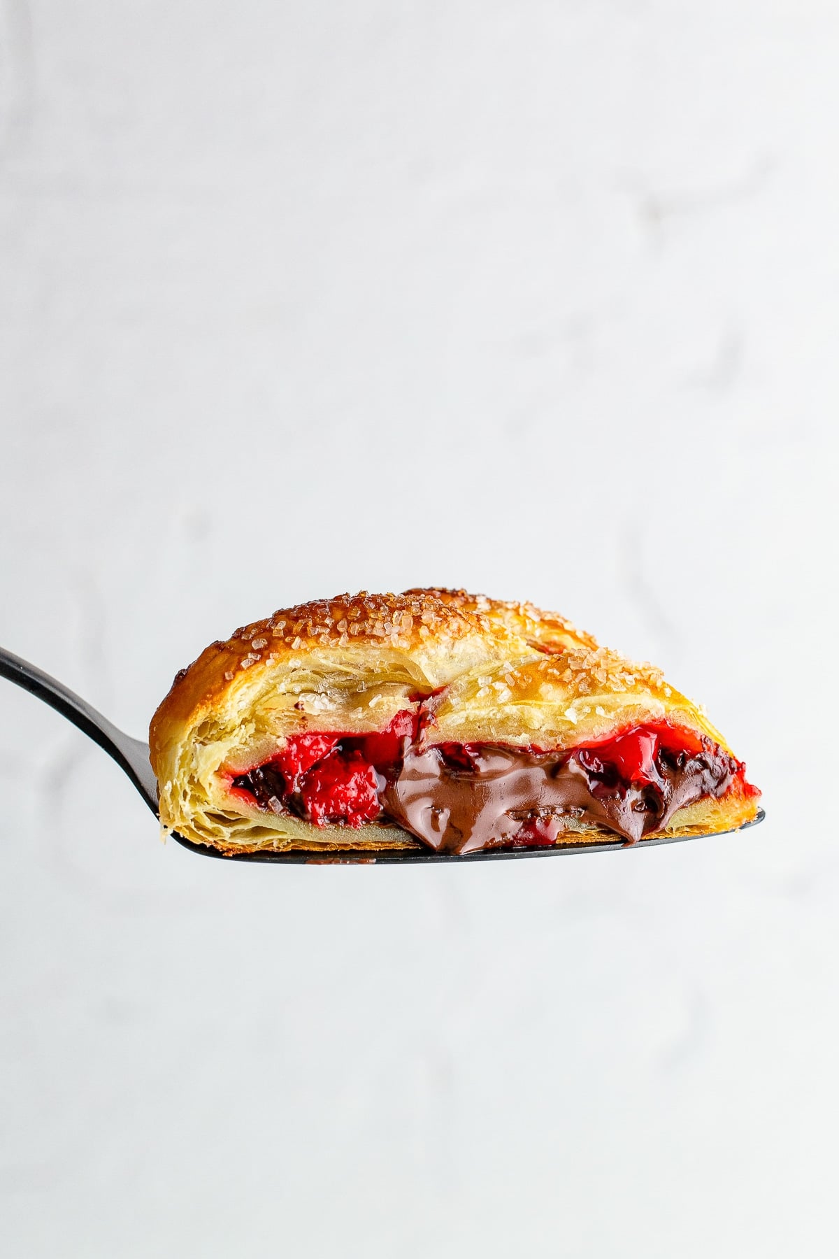 a cake server holding up a piece of Pastry Braid in air