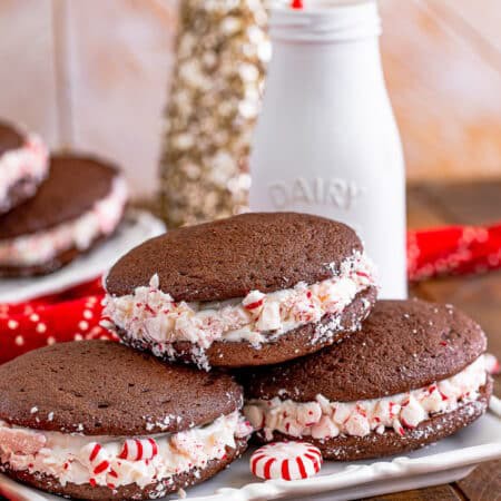A plate of chocolate Whoopie Pies with fluffy marshmallow filling rolled in crushed peppermints, milk bottle behind.