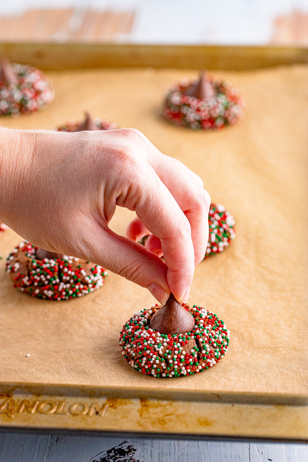 a hand placing a chocolate kiss on Blossom Cookies