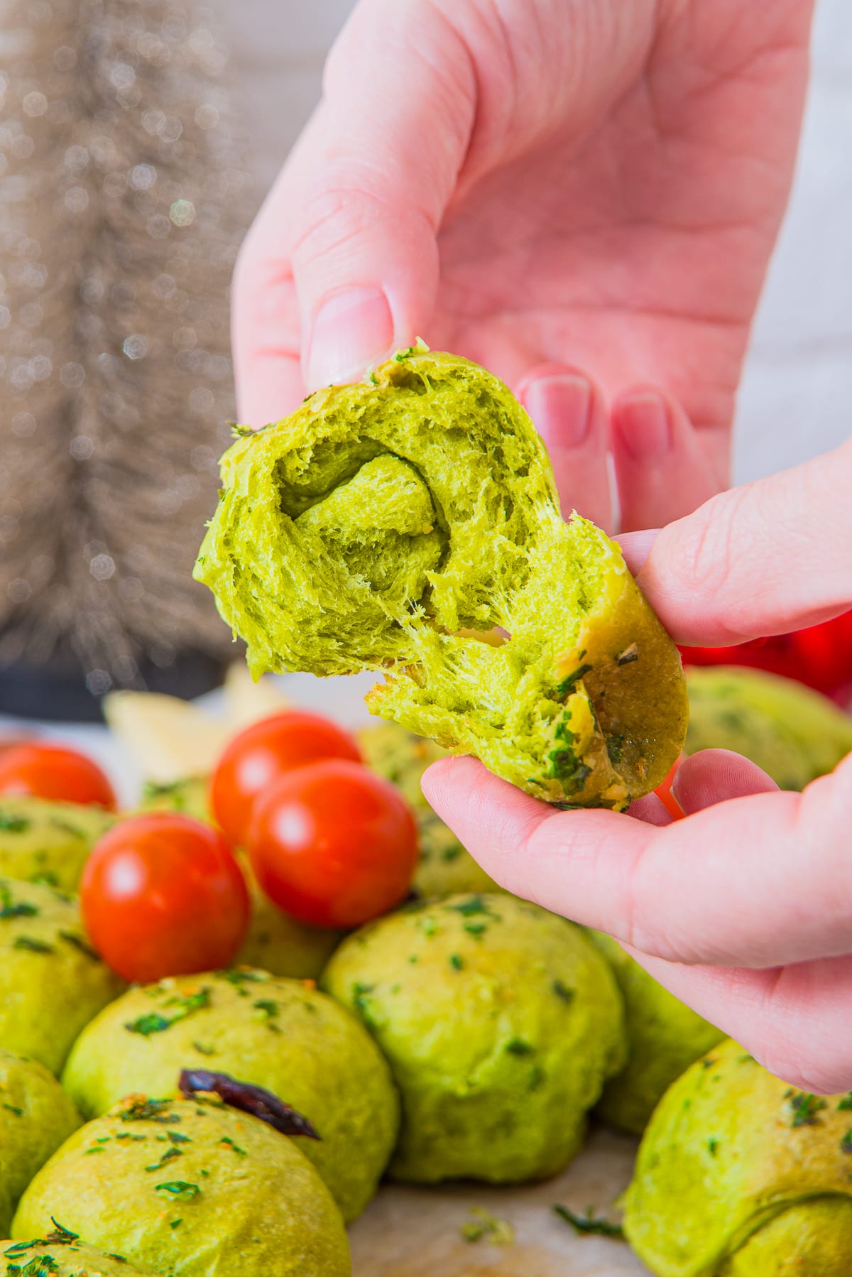 a hand holding up a piece of bread from Christmas Tree Pull Apart Bread and tearing it apart