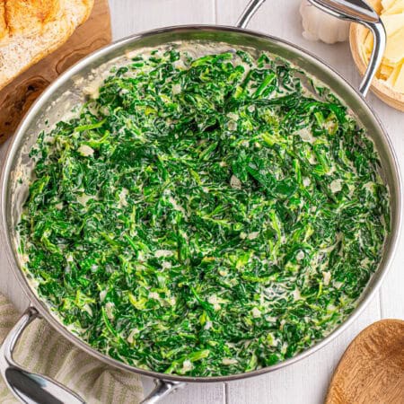 A skillet of rich, creamy steakhouse creamed spinach with shaved parmesan.