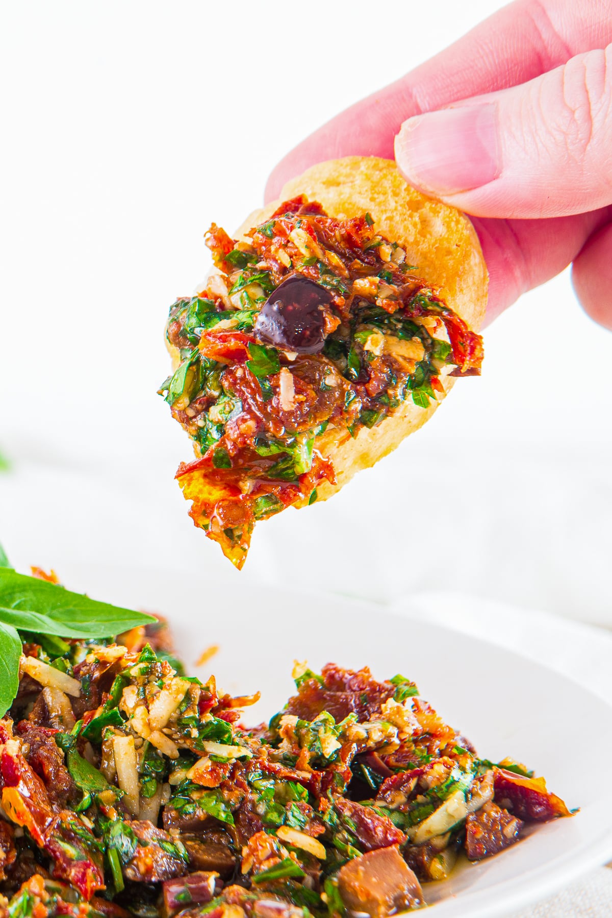 a hand holding up a toast with Mediterranean Dip on it in air