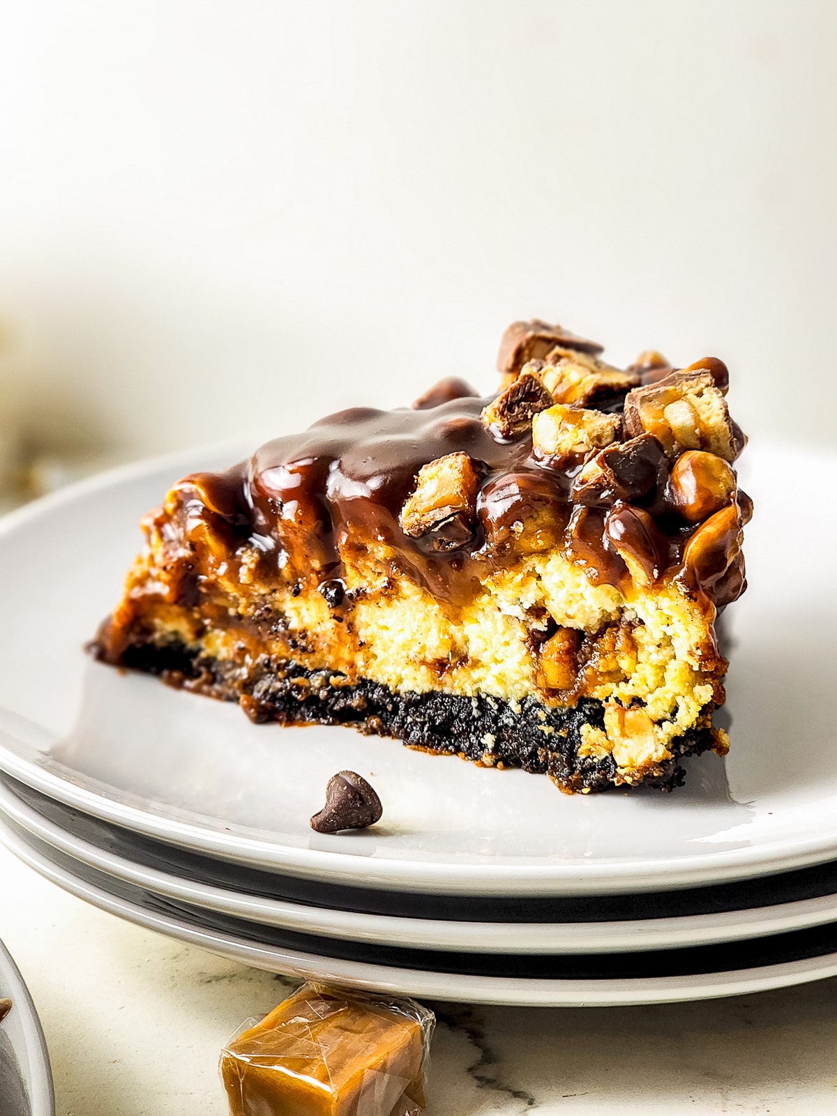 a slice of Snickers Cheesecake on a white plate