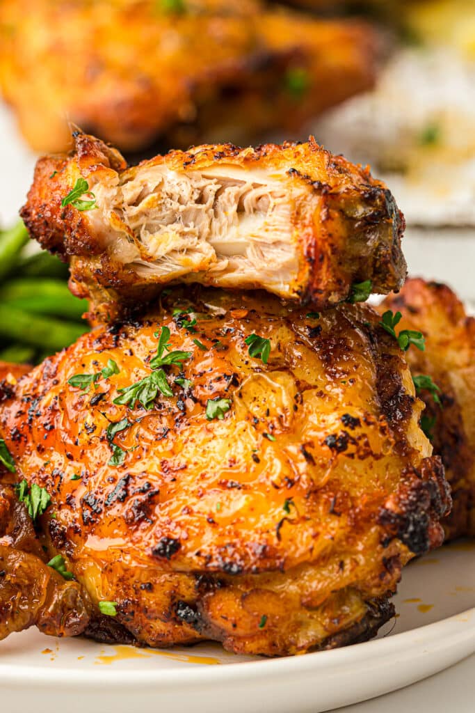 Air Fried Chicken Thigh stacked on top of each other, the one on top has a bite taken out