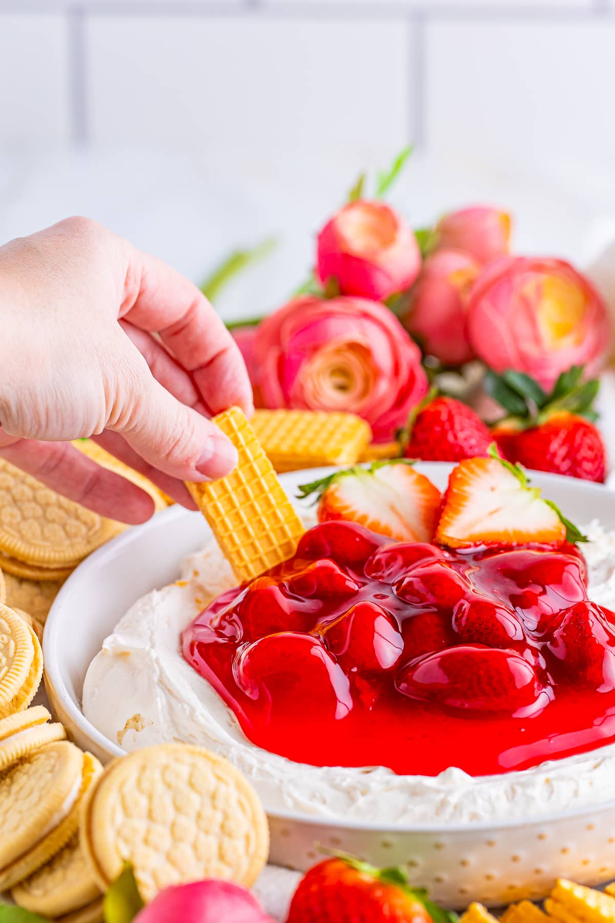 a hand dipping a cookie into Cheesecake Dip