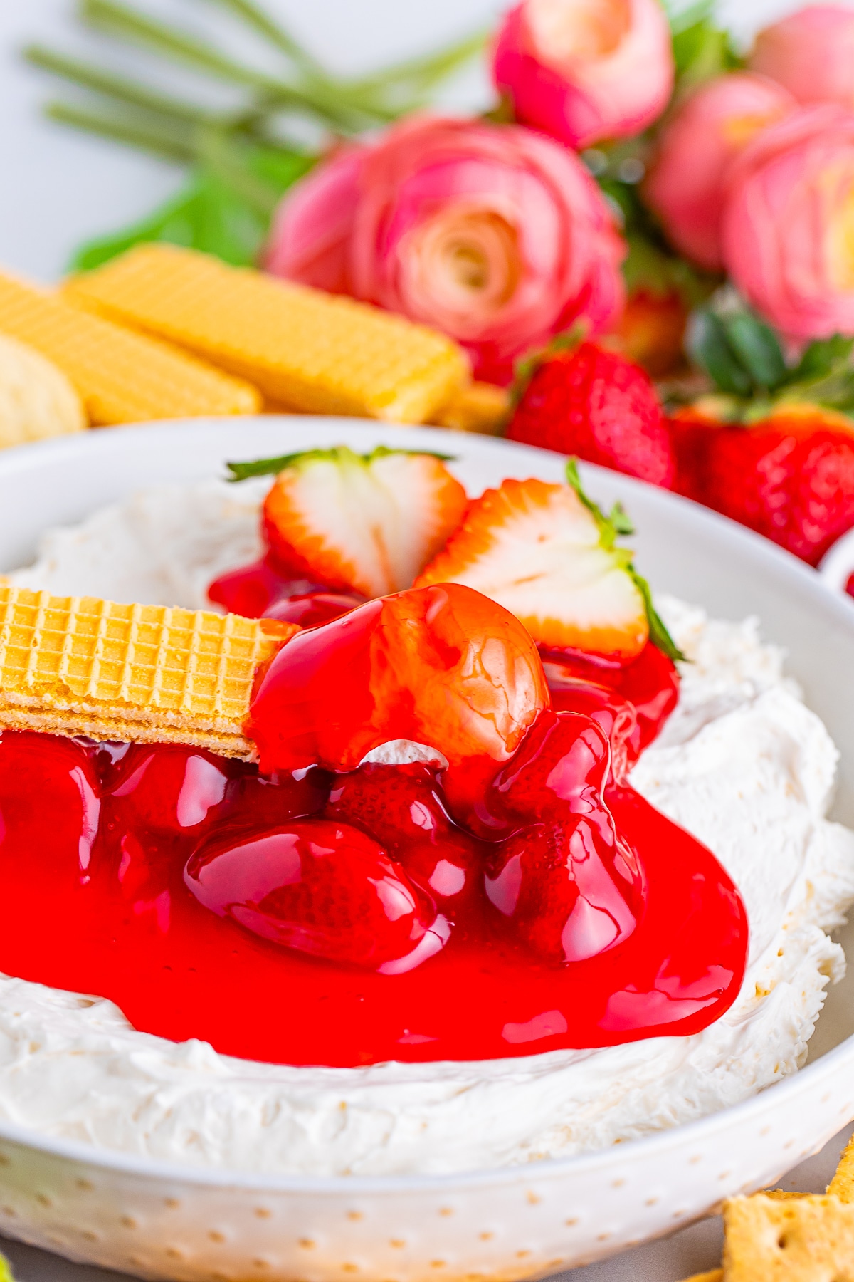 a cookie that has been dipped in Cheesecake Dip sitting on top of the bowl