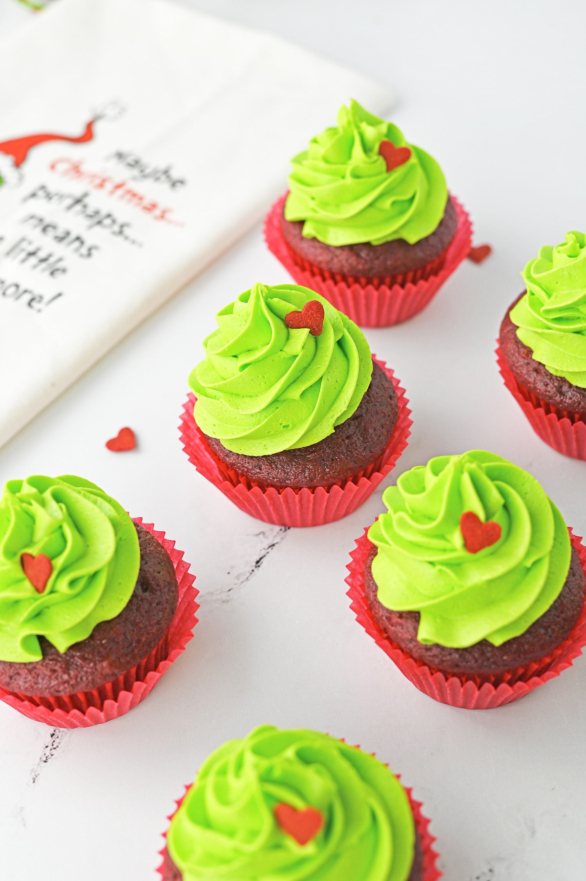 a bunch of Grinch Cupcakes on a white table top