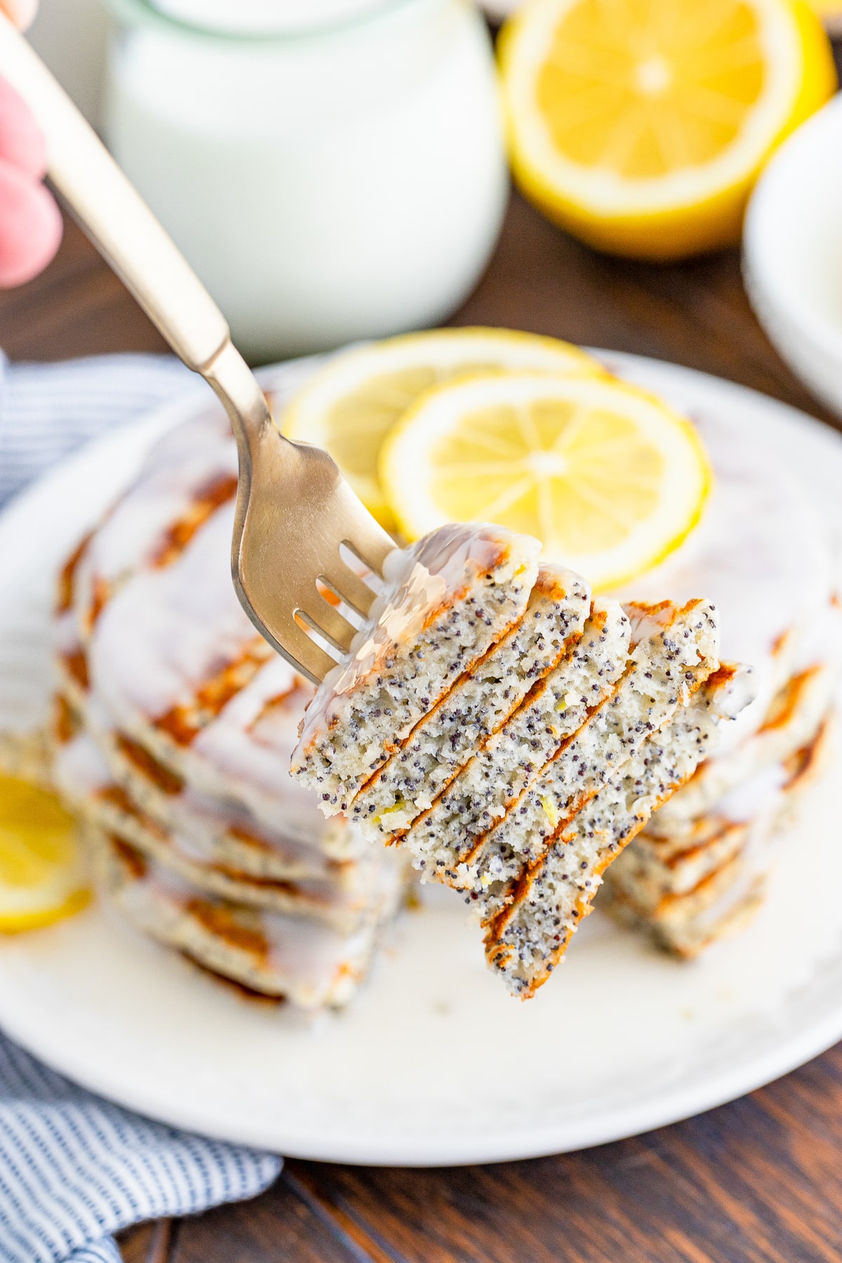 a fork holding up a bite of Lemon poppy seed pancakes in air