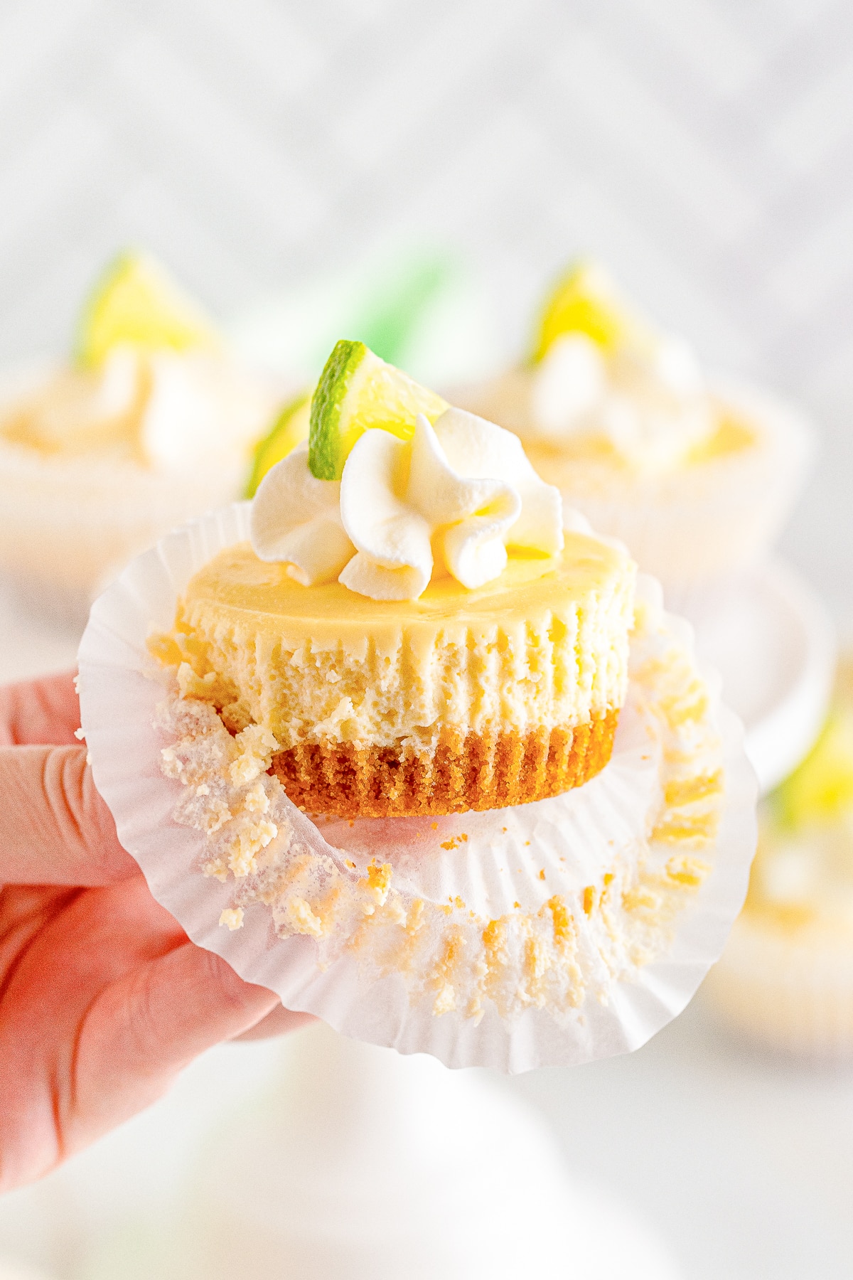 a hand holding up Mini Cheesecakes in air