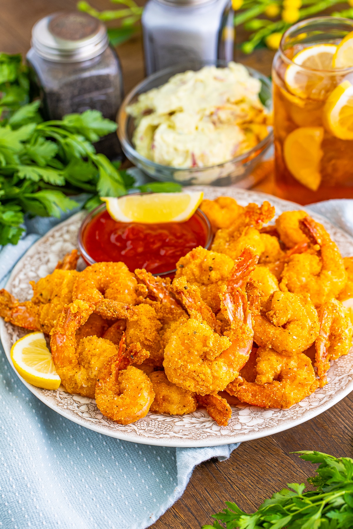 a bunch of Fried Shrimp on a tan plate with blue linen