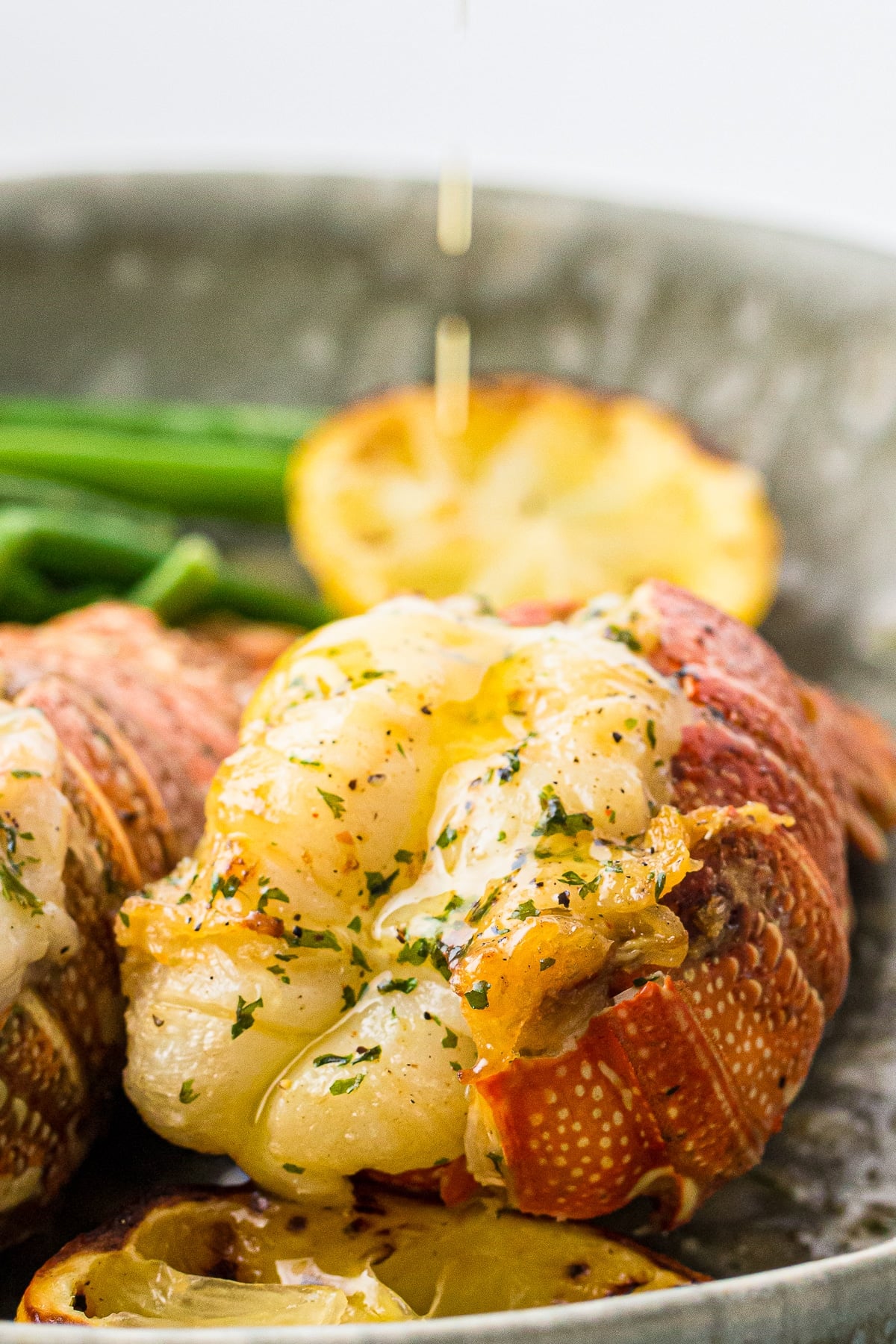 Air Fryer Lobster Tails on a platter with butter being poured on top
