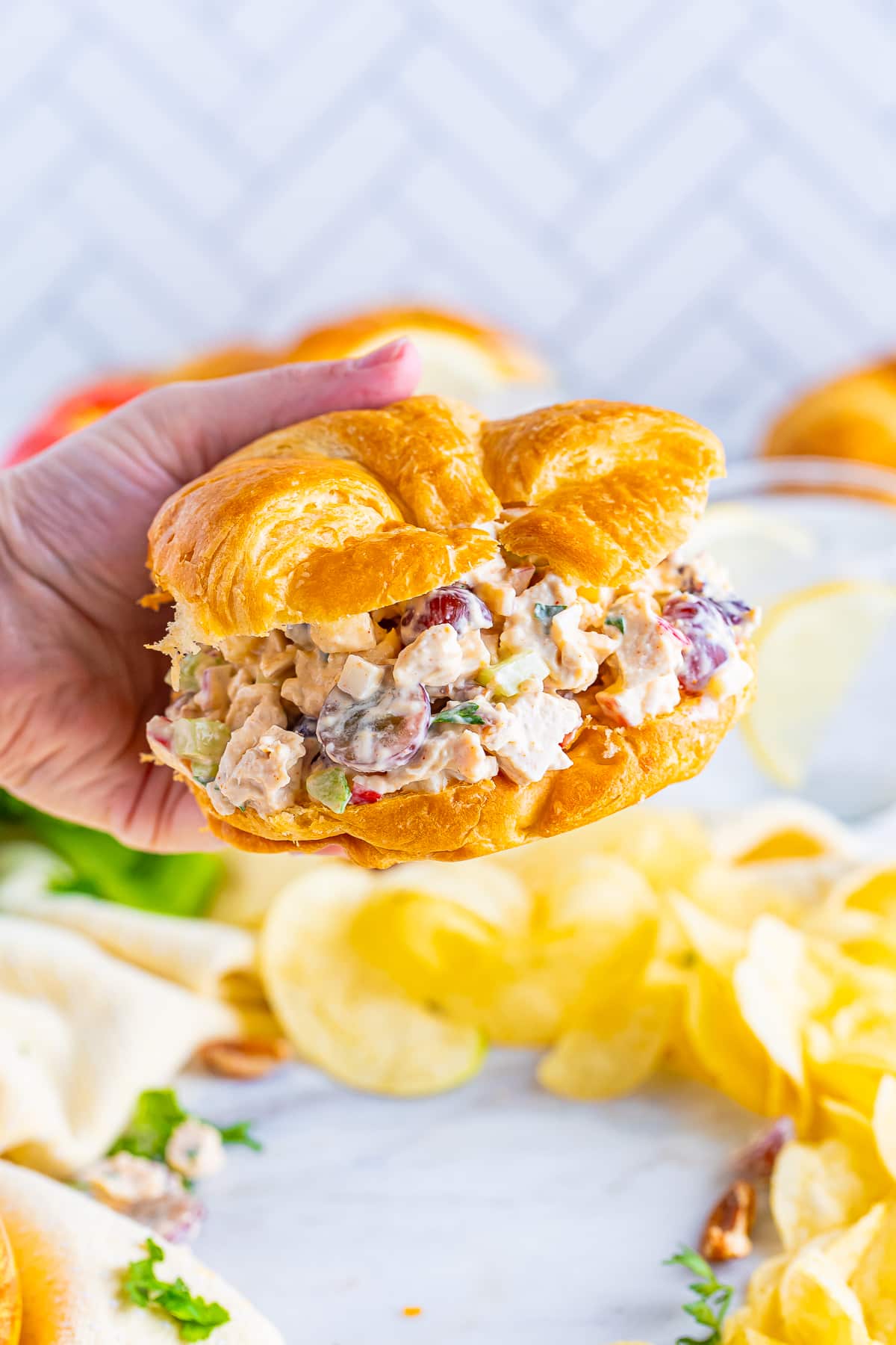 a hand holding up a Chicken Salad Recipe on croissant 