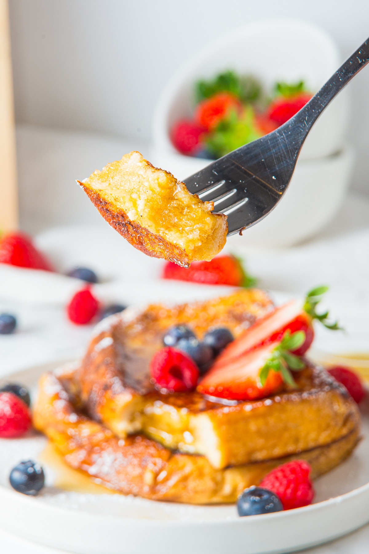 a fork holding up a bite of French toast recipe in air 