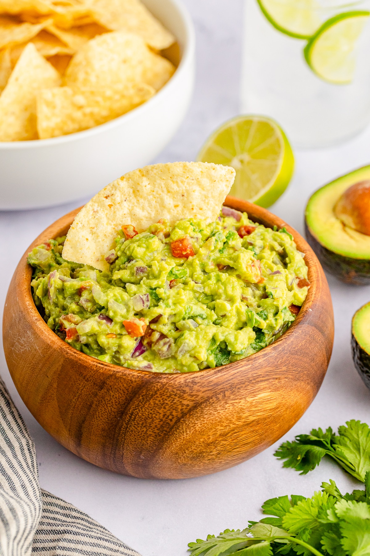 guacamole in a wooden bowl with a chip in it