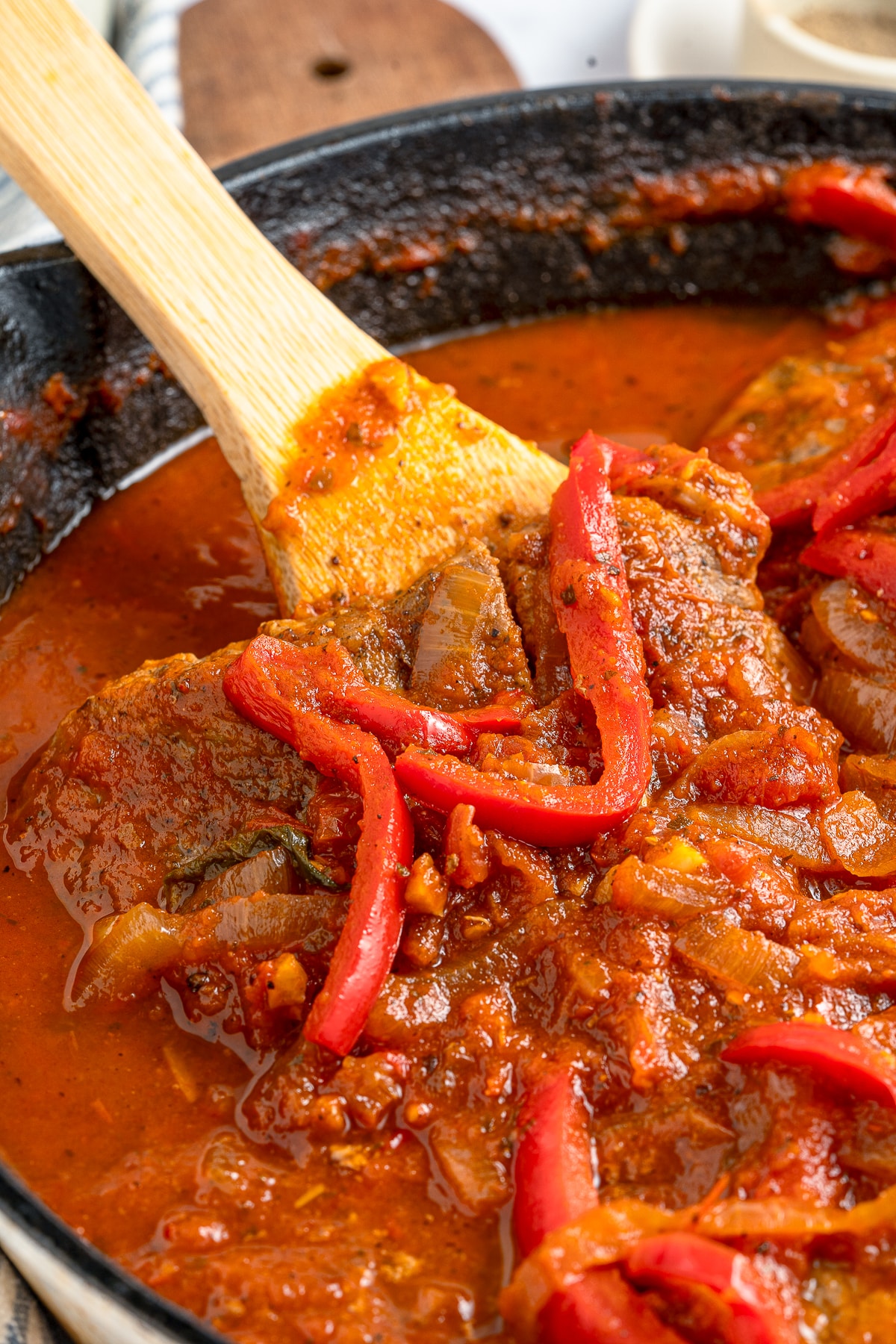a spoon getting a portion of Steak Pizzaiola out of pan