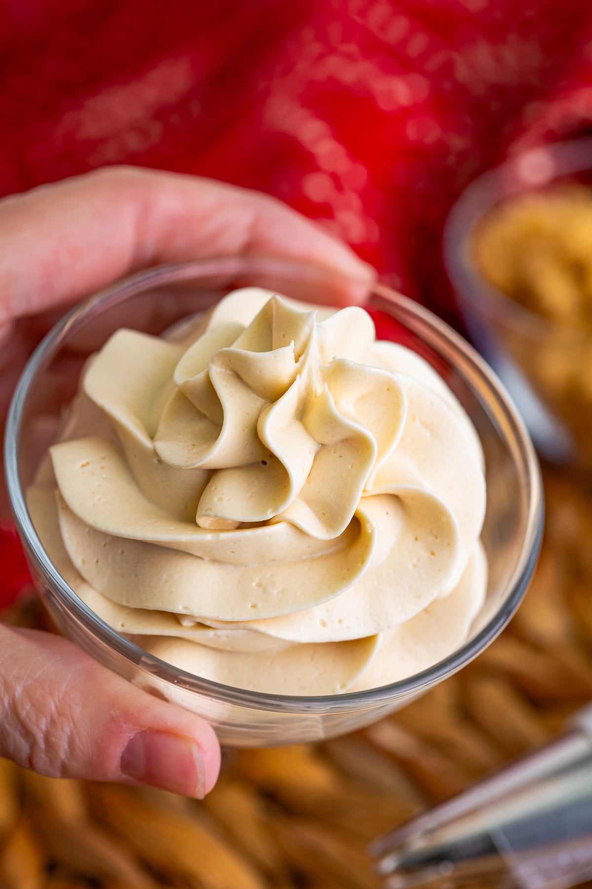 a hand holding up a cup with Brown Sugar Frosting piped into it