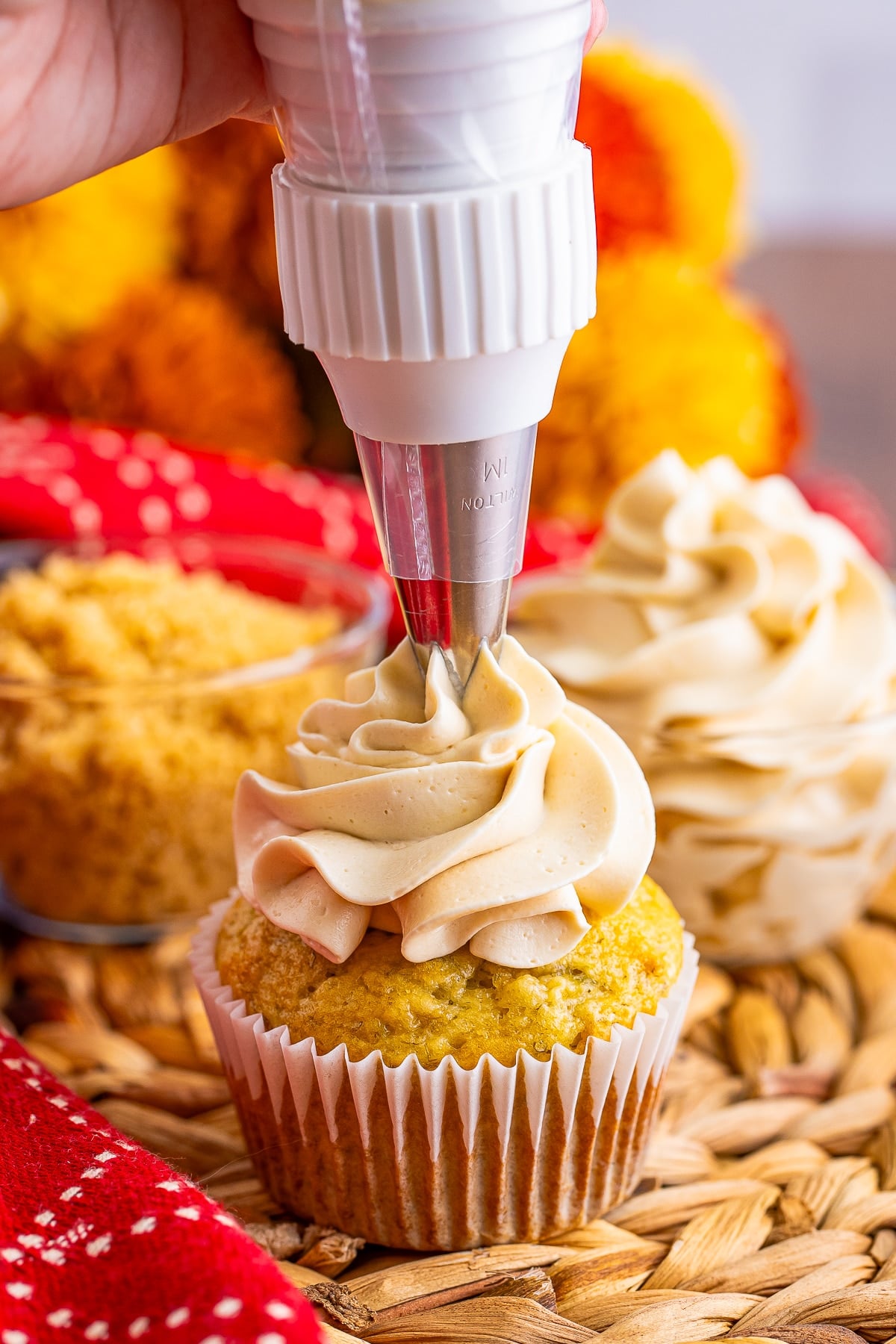 a piping bag piping Brown Sugar Frosting on to a cupcake