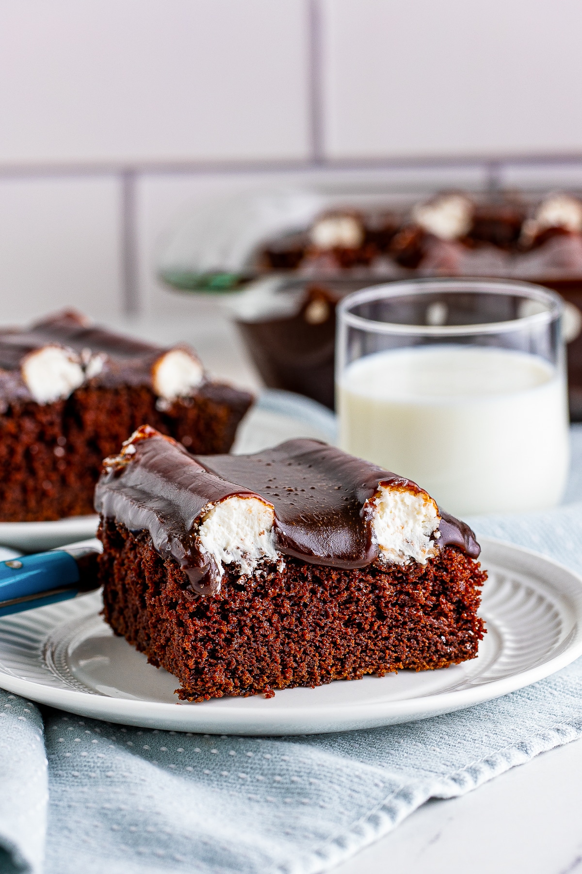 a slice of Bumpy Cake on a white plate with glass of milk