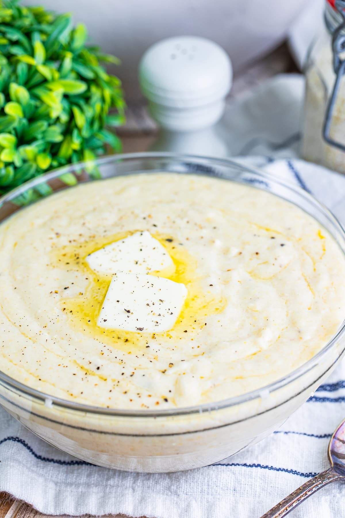finished grits in a clear bowl with butter on top