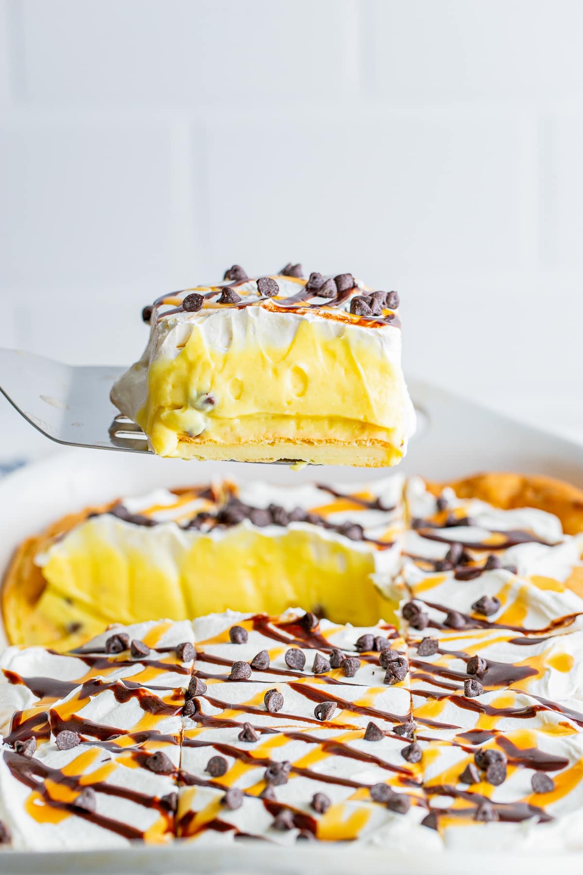 a spatula holding up a slice of Cream Puff Cake in air