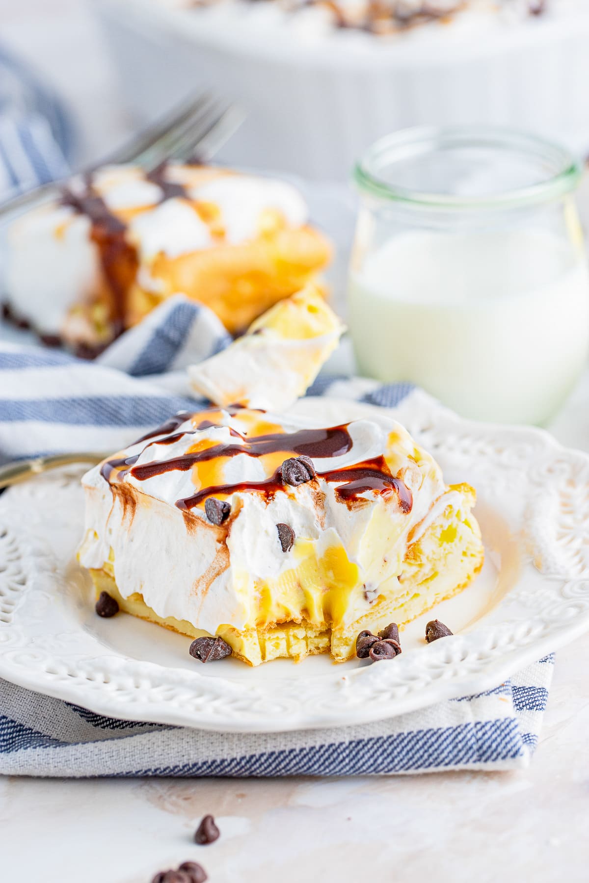 a slice of Cream Puff Cake on a plate with a bite taken out