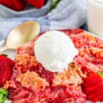 A serving of Strawberry Dump Cake on a plate topped with a scoop of vanilla ice cream.