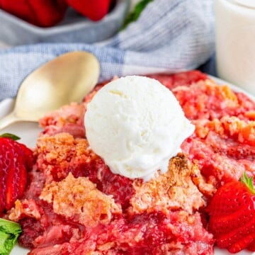 A serving of Strawberry Dump Cake on a plate topped with a scoop of vanilla ice cream.