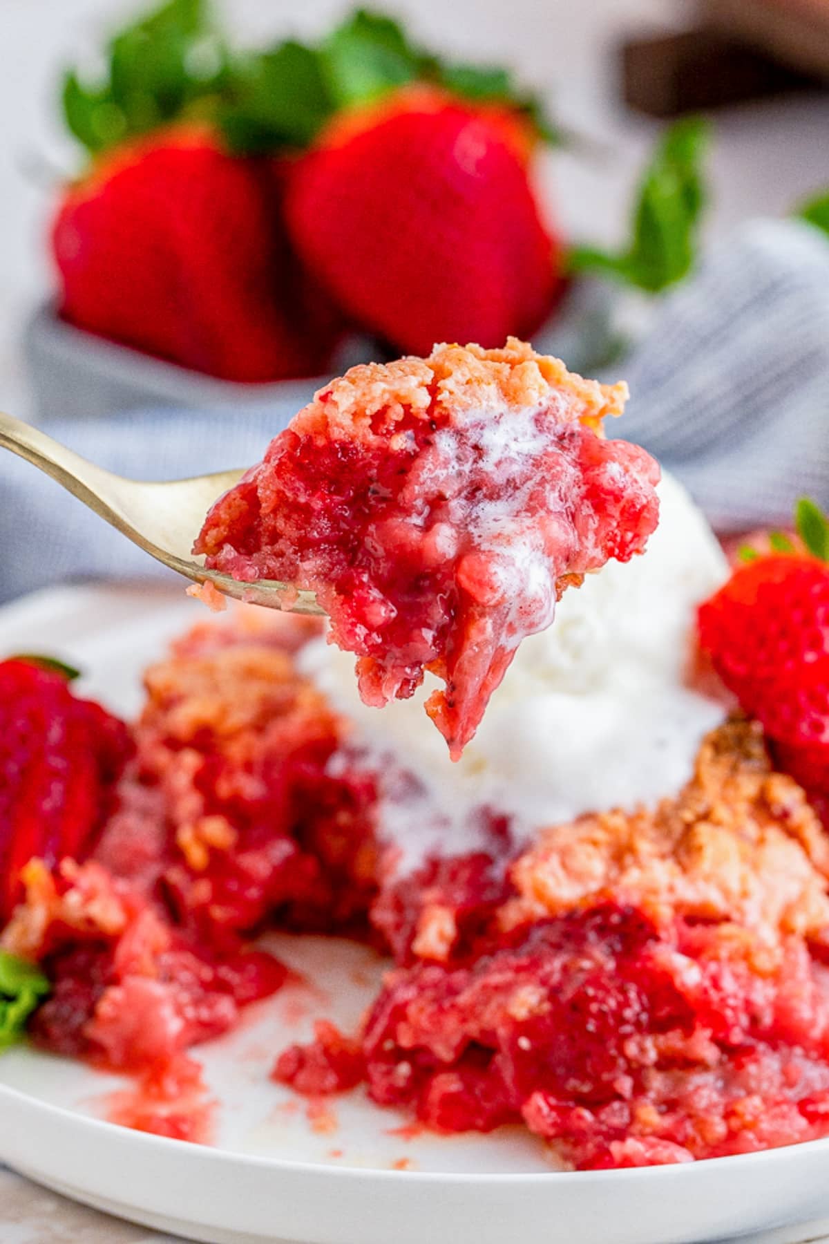 a spoon holding up a bite of Strawberry Dump Cake in air