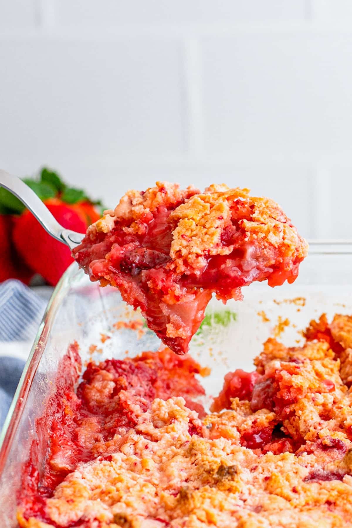 a spoon holding up a portion of Strawberry Dump Cake in air