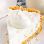 A slice of no bake coconut cream pie with a dollop of whipped cream on top and a golden coconut graham cracker crust.