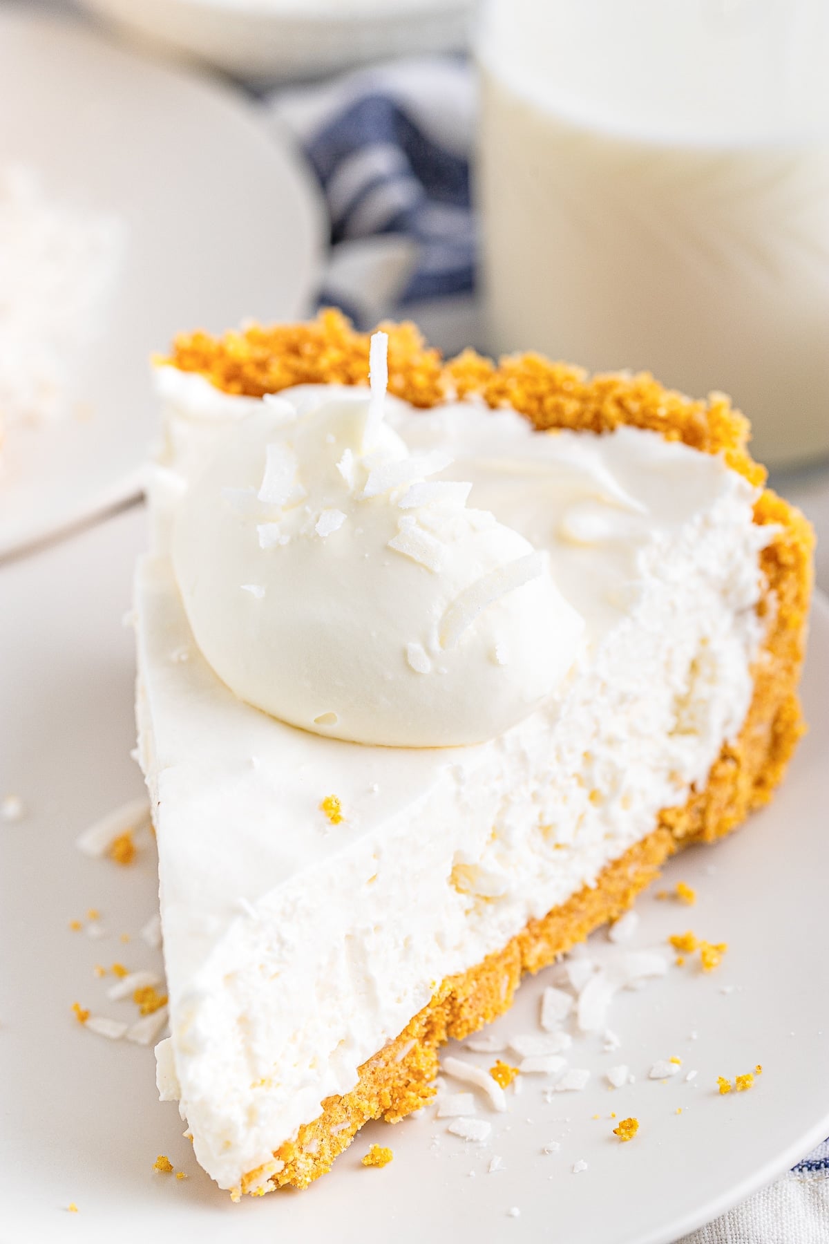 close up of a slice of coconut cream pie on white plate