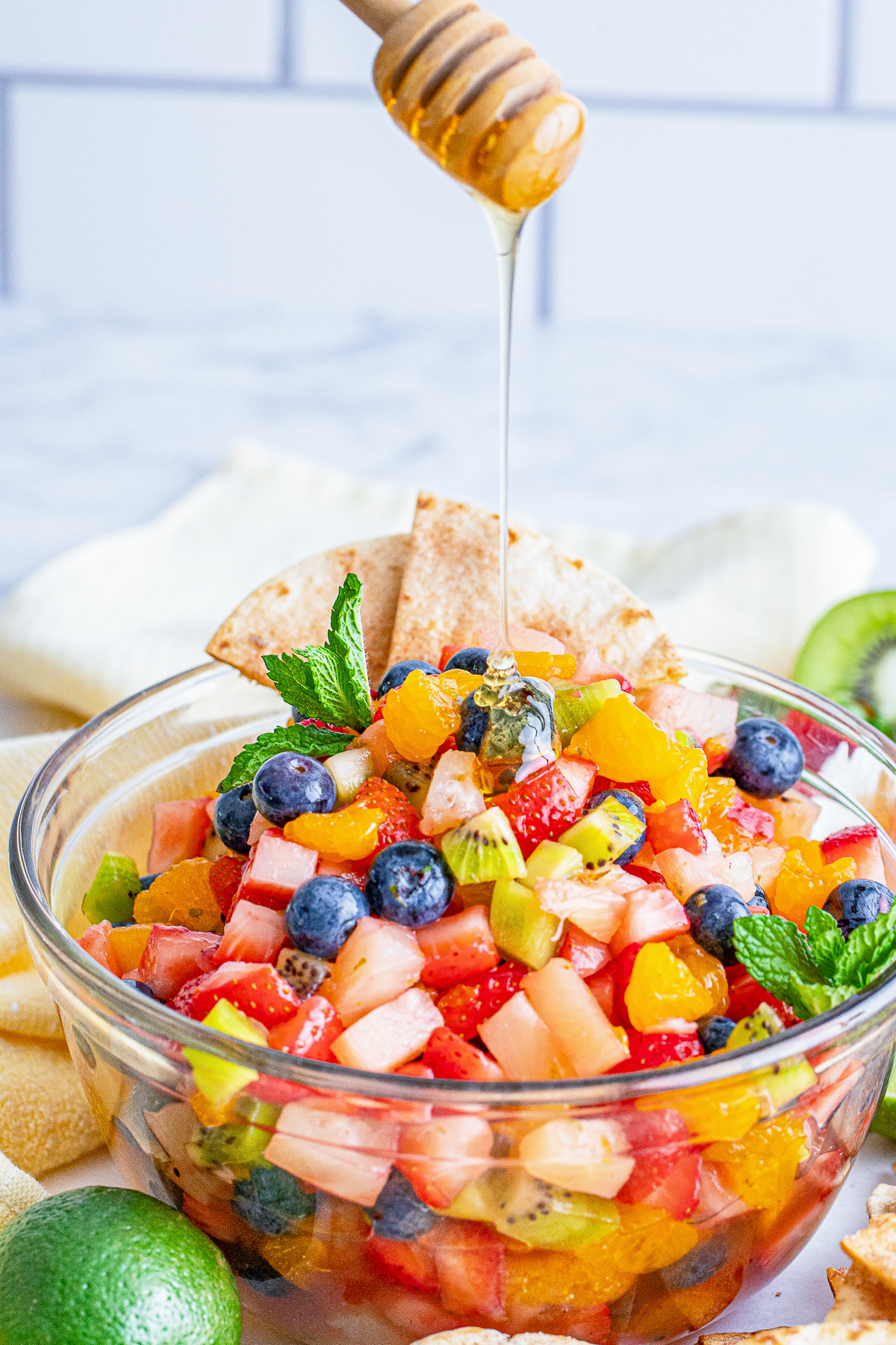 honey drizzling over a bowl of fruit salsa
