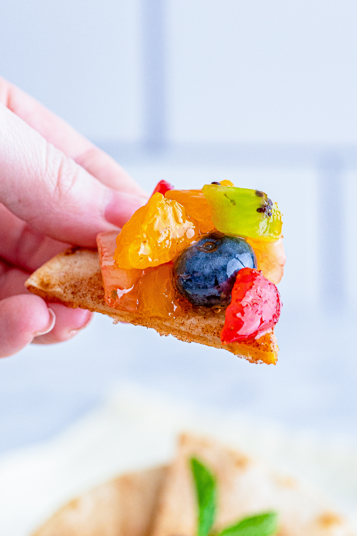 a hand holding up a tortilla with fruit salsa on it