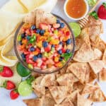 A bowl of colorful fruit salsa with strawberries, blueberries, kiwi, and pineapple served with baked cinnamon tortilla chips.