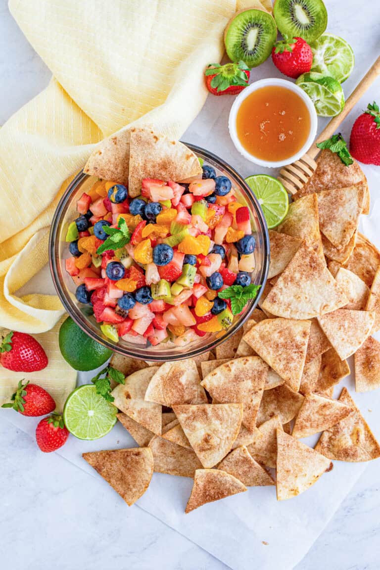 A bowl of colorful fruit salsa with strawberries, blueberries, kiwi, and pineapple served with baked cinnamon tortilla chips.