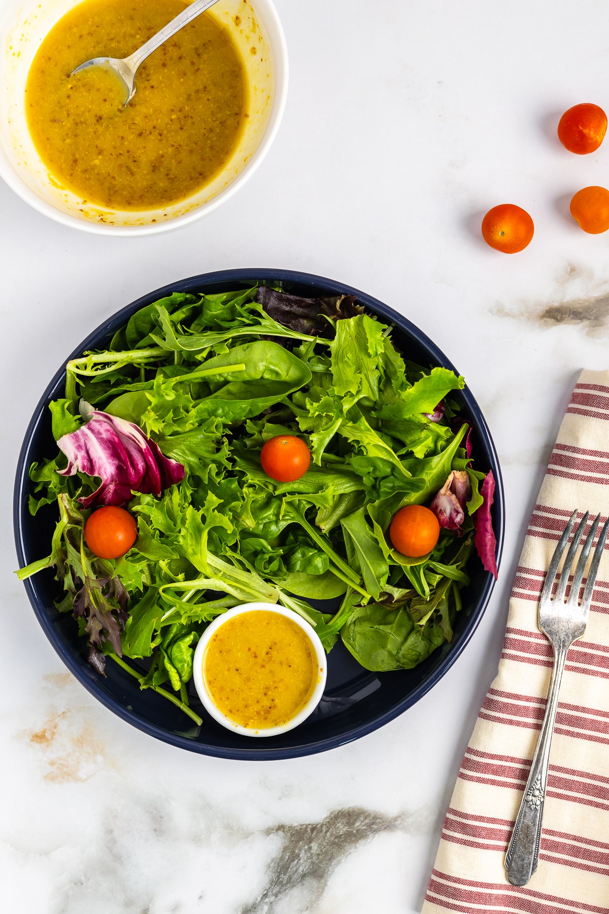 a salad with a small ramekin full of Honey Mustard Dressing Recipe on it
