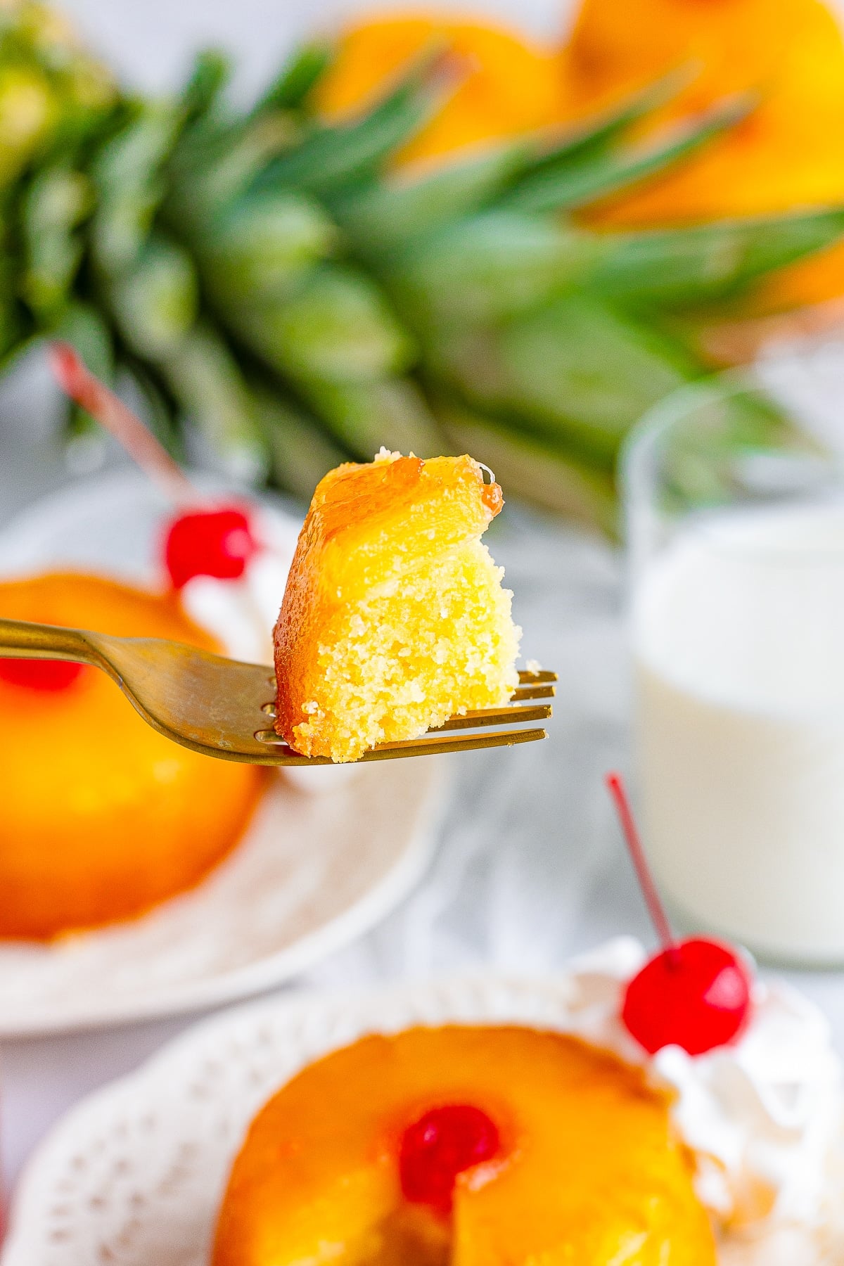 a fork holding up a bite of Mini Pineapple Upside Down Cakes in air