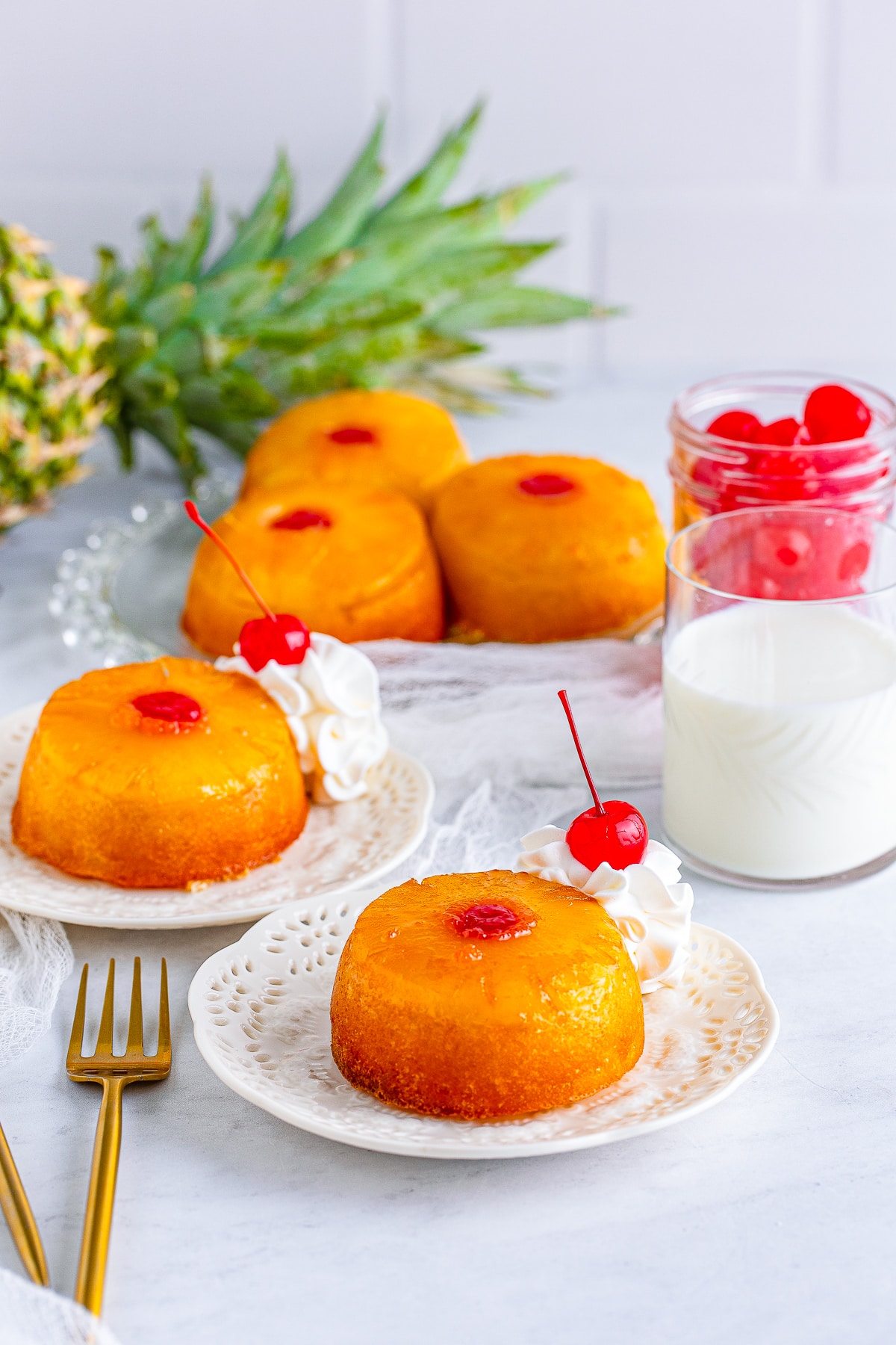 farther away image of Mini Pineapple Upside Down Cakes on plates with garnishes