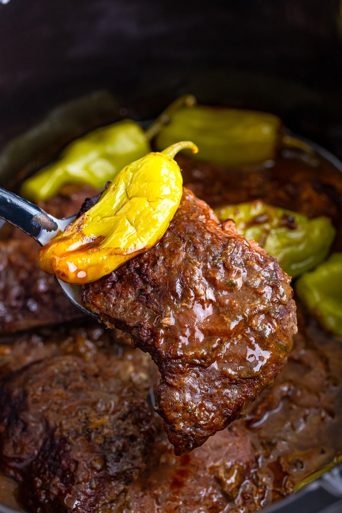 a spoon holding up Beef Cubed Steaks in air over slow cooker