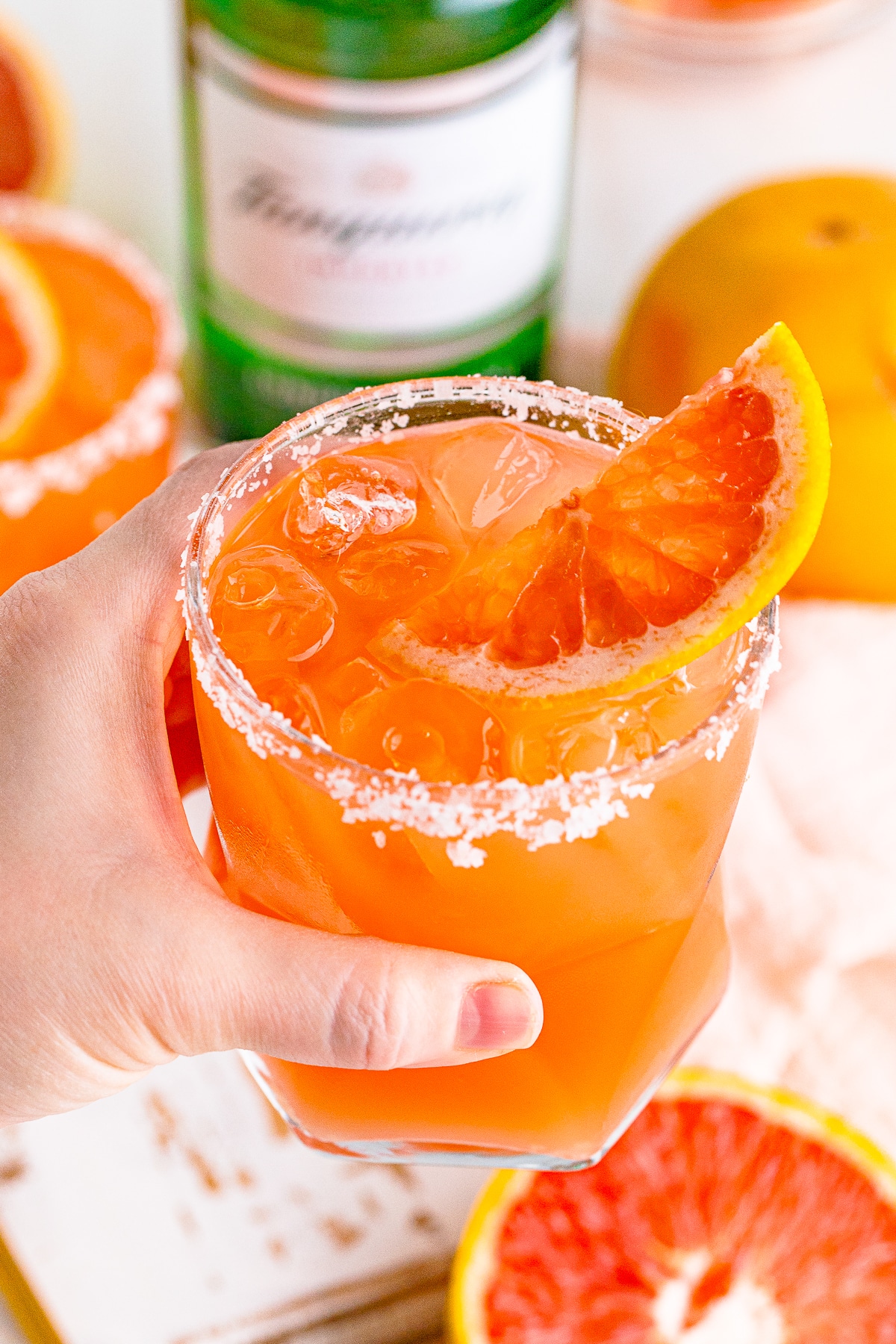 a hand holding up a glass of salty dog in air